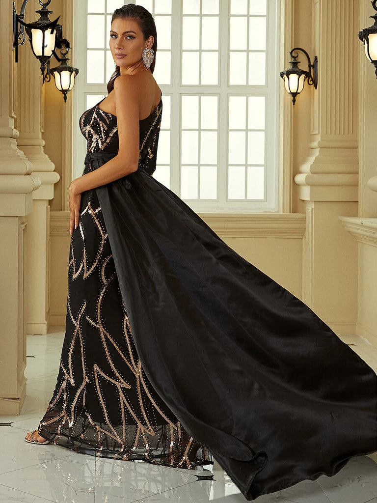 An Elegant black one-shoulder gown featuring intricate sequin detailing, a gold belt accent, and a dramatic cape for a regal and sophisticated look.