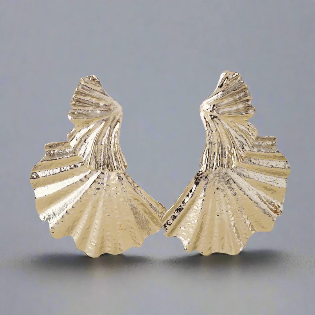 Silver-tone statement earring with a textured, fan-like design. The earring features multiple layered, shell-inspired shapes with intricate ridged details, adding an elegant yet bold look. The matte finish and unique structure give the earring a refined, sculptural aesthetic.