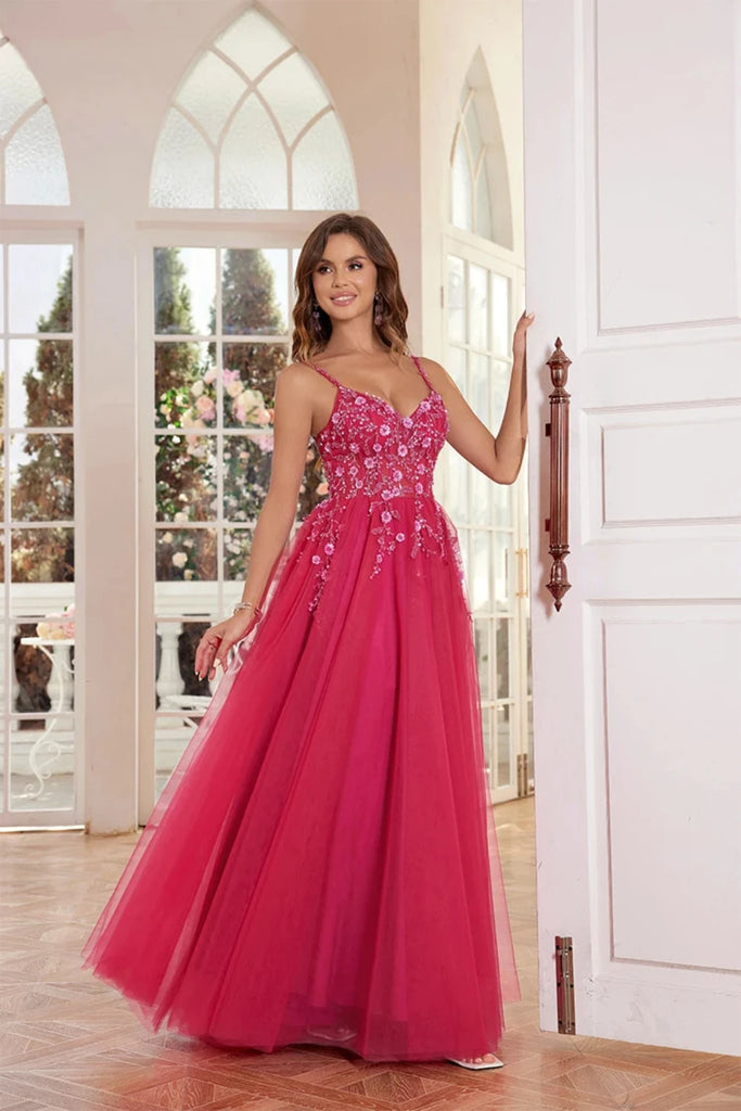 An elegant pink tulle ball gown features a fitted bodice adorned with delicate floral appliqués and thin straps. The full, flowing skirt adds a fairytale touch, perfect for proms, formal events, or weddings.