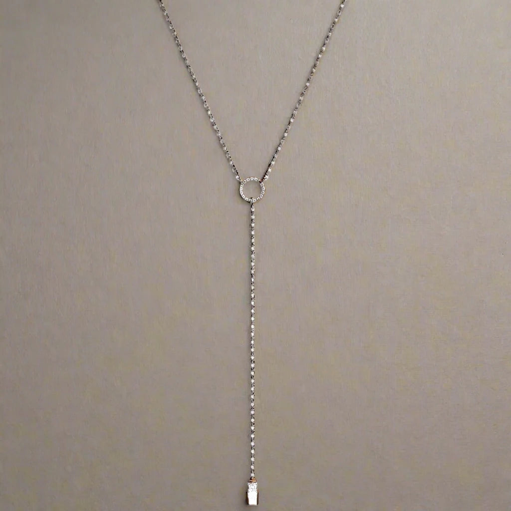 A delicate layered necklace featuring two slim silver-tone chains, each adorned with a minimalist circle pendant, with the lower chain extending into a Y-shaped drop for an elegant and refined look.