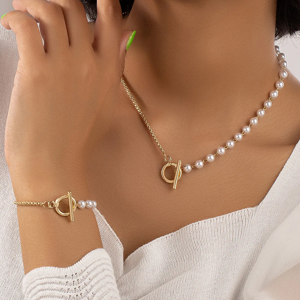 stylish jewelry set featuring a necklace and bracelet, combining classic pearls with a modern gold-tone chain and toggle clasp, offering a chic and elegant accessory perfect for any occasion.