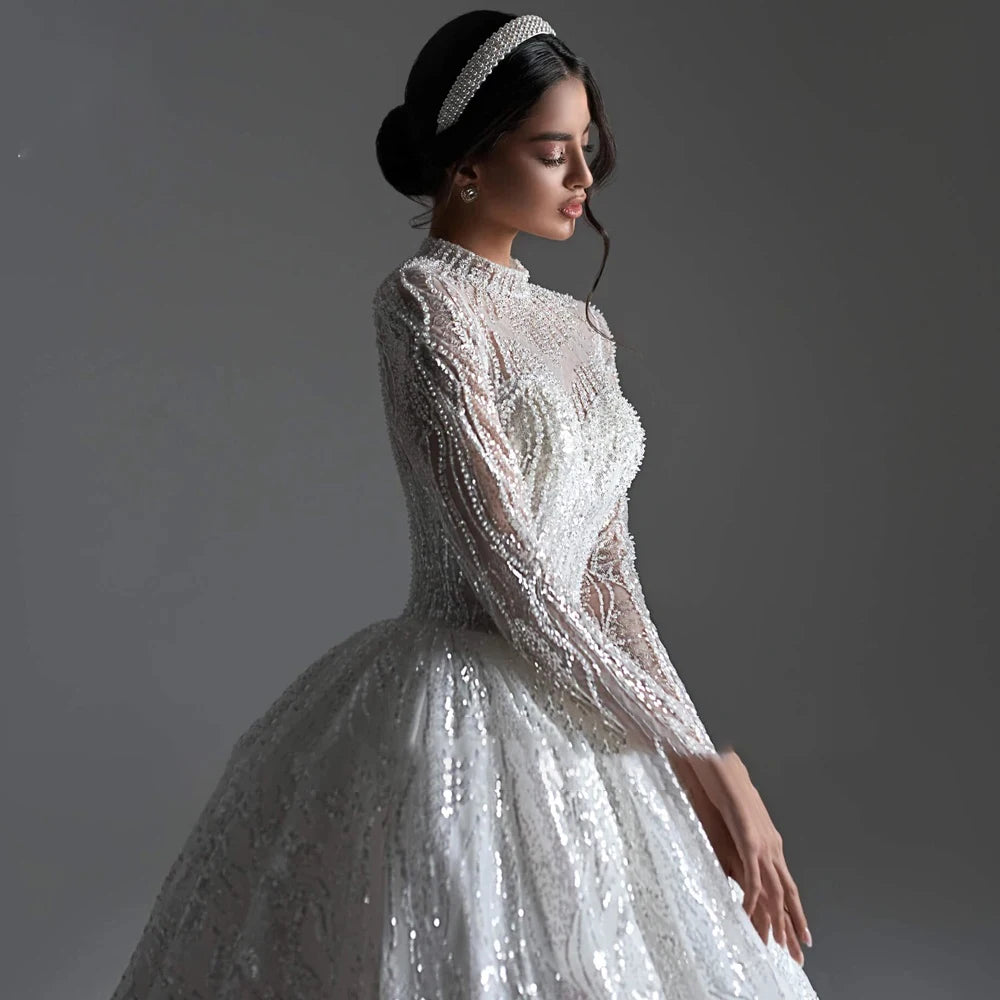 High V-neck long sleeve ball gown wedding dress with lace appliques and beaded details, available in ivory and white.