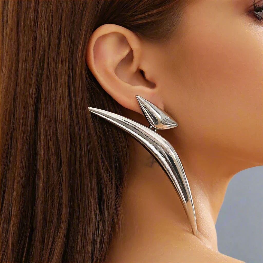 Striking Silver-tone earrings featuring a bold, angular design that extends dramatically along the ear, creating a modern and edgy statement piece.