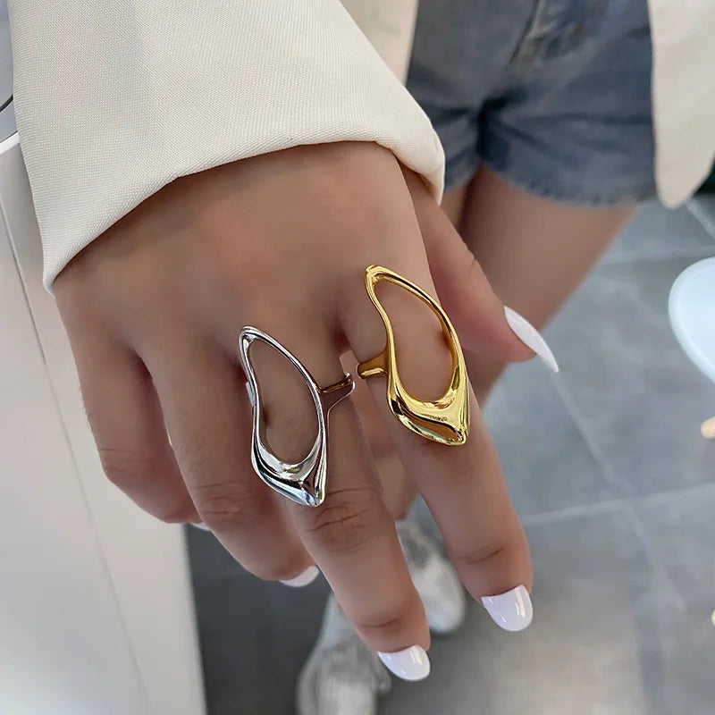 A pair of sculptural, open-design rings in polished gold and silver tones, showcasing a bold and modern aesthetic contemporary look.