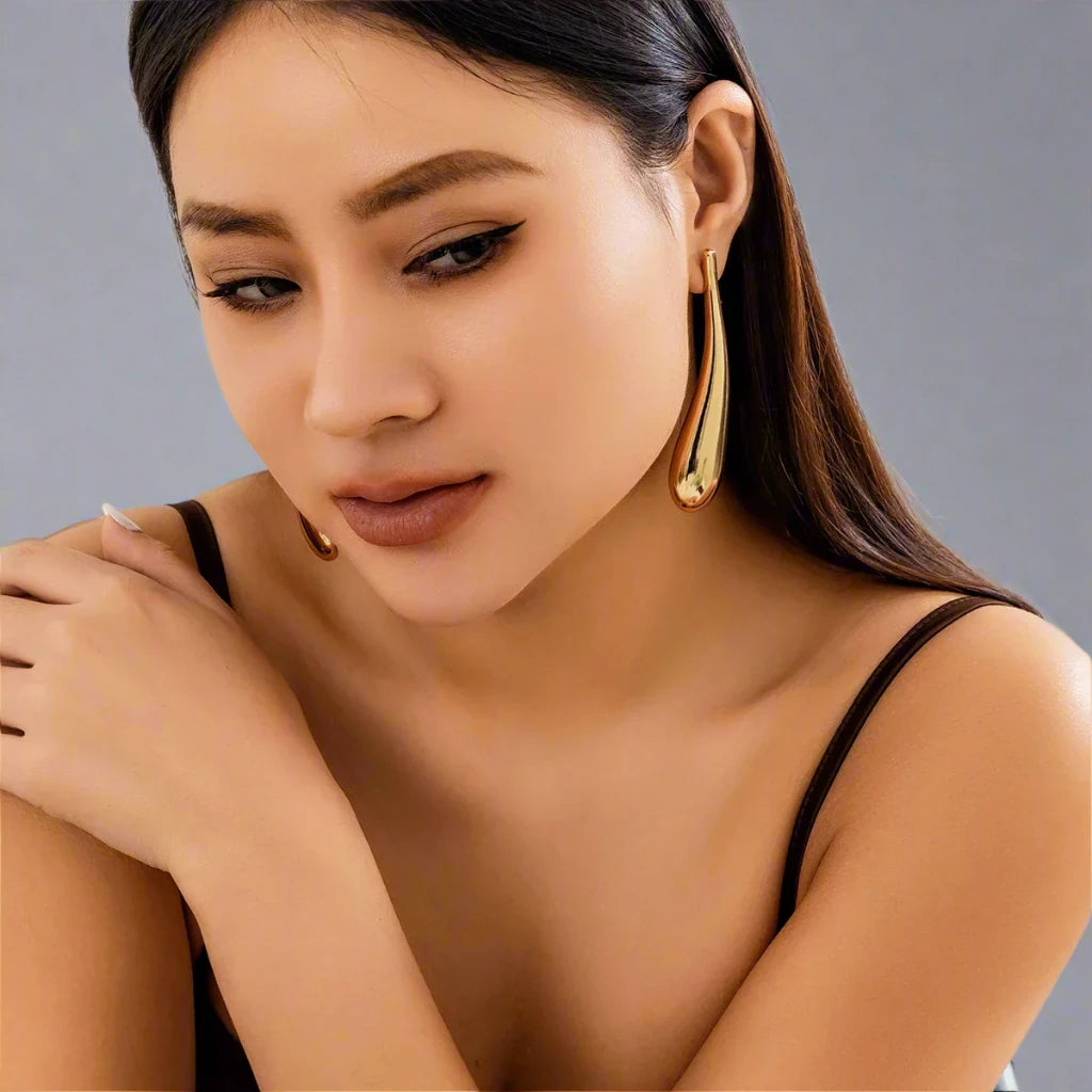 A sleek and modern gold-tone earring featuring an elongated teardrop design, adding a touch of sophistication and elegance to any look.