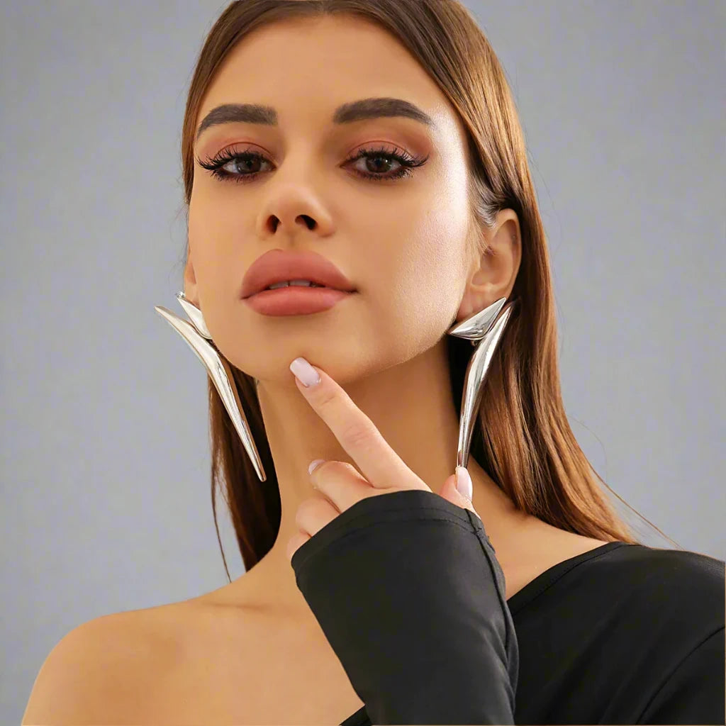 Striking Silver-tone earrings featuring a bold, angular design that extends dramatically along the ear, creating a modern and edgy statement piece.