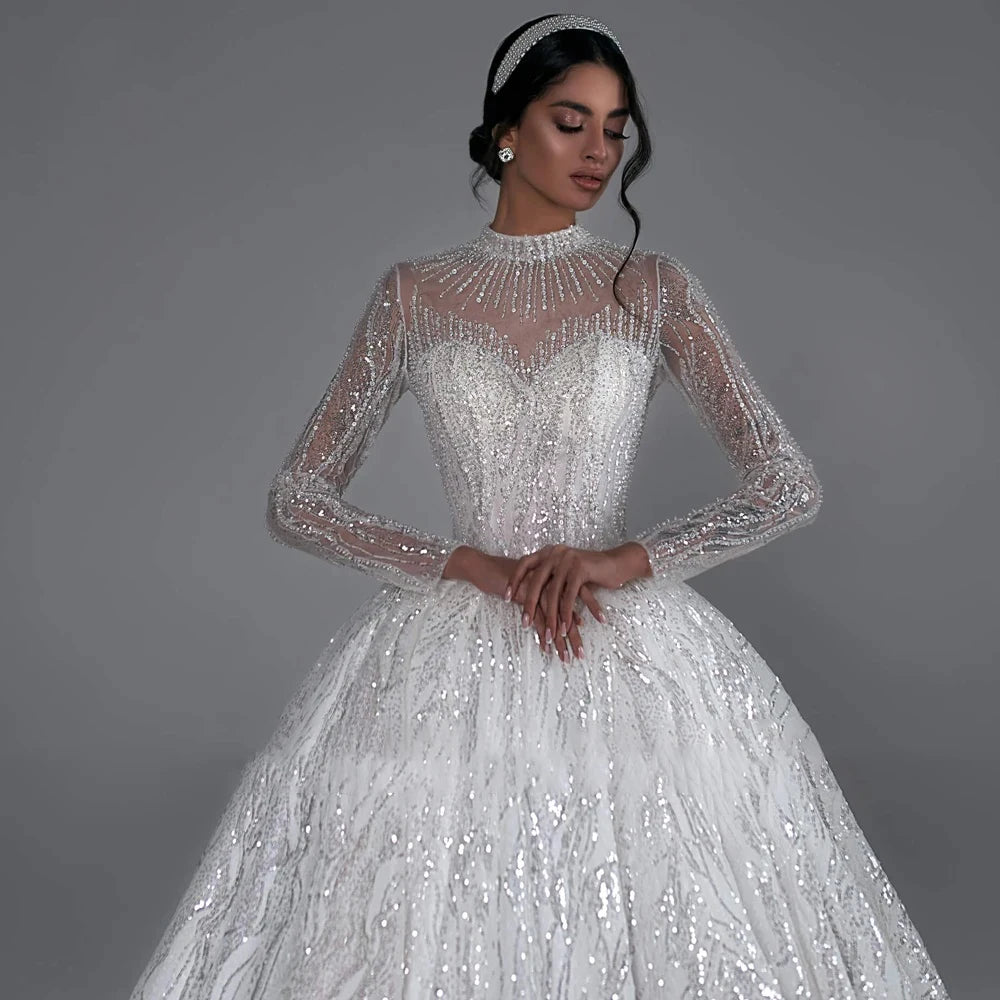 High V-neck long sleeve ball gown wedding dress with lace appliques and beaded details, available in ivory and white.