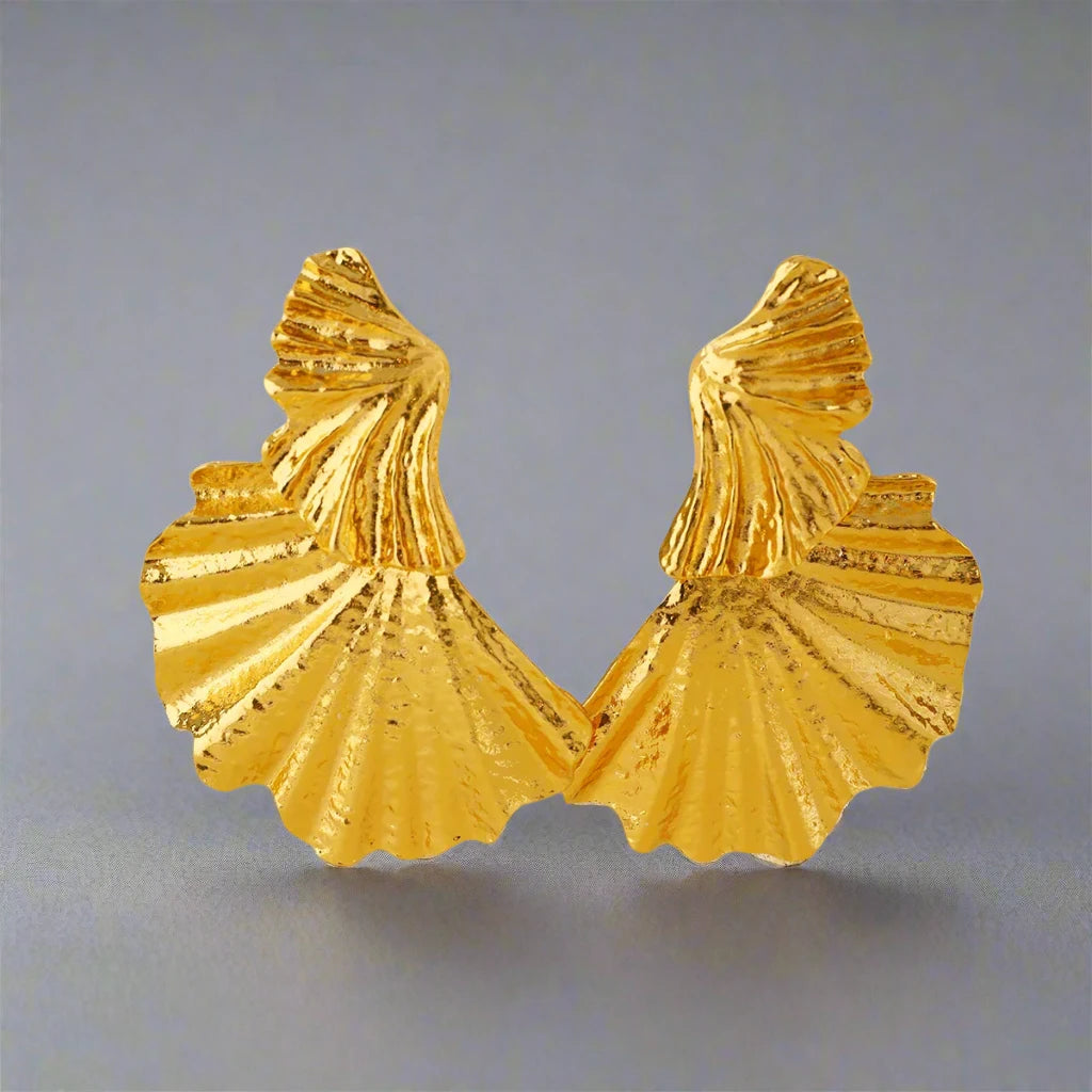 Gold-tone statement earring with a textured, fan-like design. The earring features multiple layered, shell-inspired shapes with intricate ridged details, adding an elegant yet bold look. The matte finish and unique structure give the earring a refined, sculptural aesthetic.