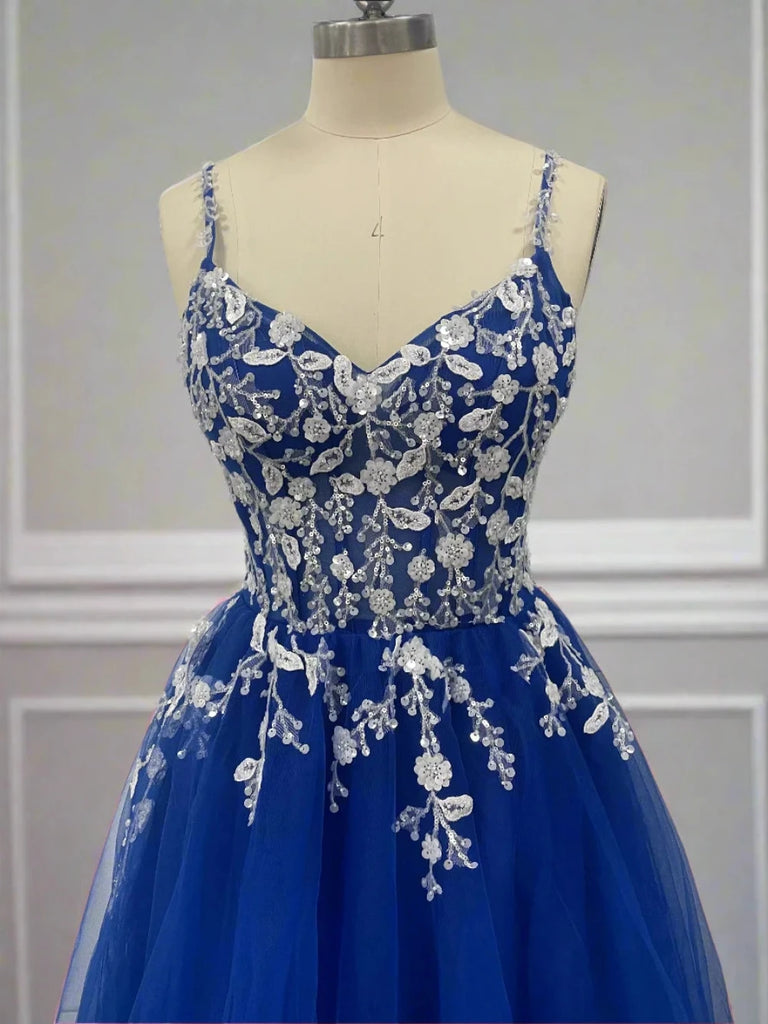 An elegant blue tulle ball gown features a fitted bodice adorned with delicate floral appliqués and thin straps. The full, flowing skirt adds a fairytale touch, perfect for proms, formal events, or weddings.