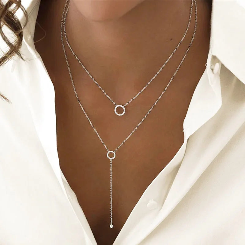 A delicate layered necklace featuring two slim silver-tone chains, each adorned with a minimalist circle pendant, with the lower chain extending into a Y-shaped drop for an elegant and refined look.