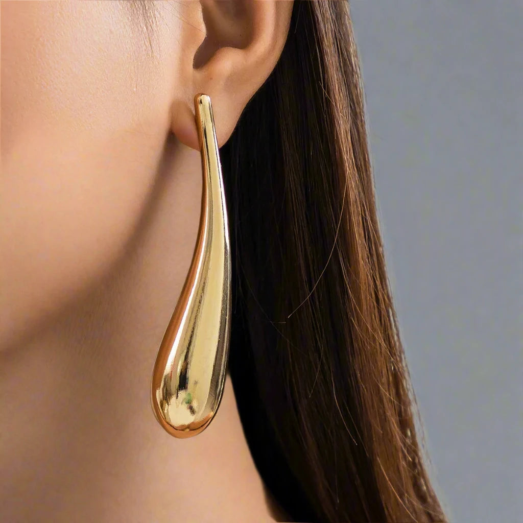 A sleek and modern gold-tone earring featuring an elongated teardrop design, adding a touch of sophistication and elegance to any look.