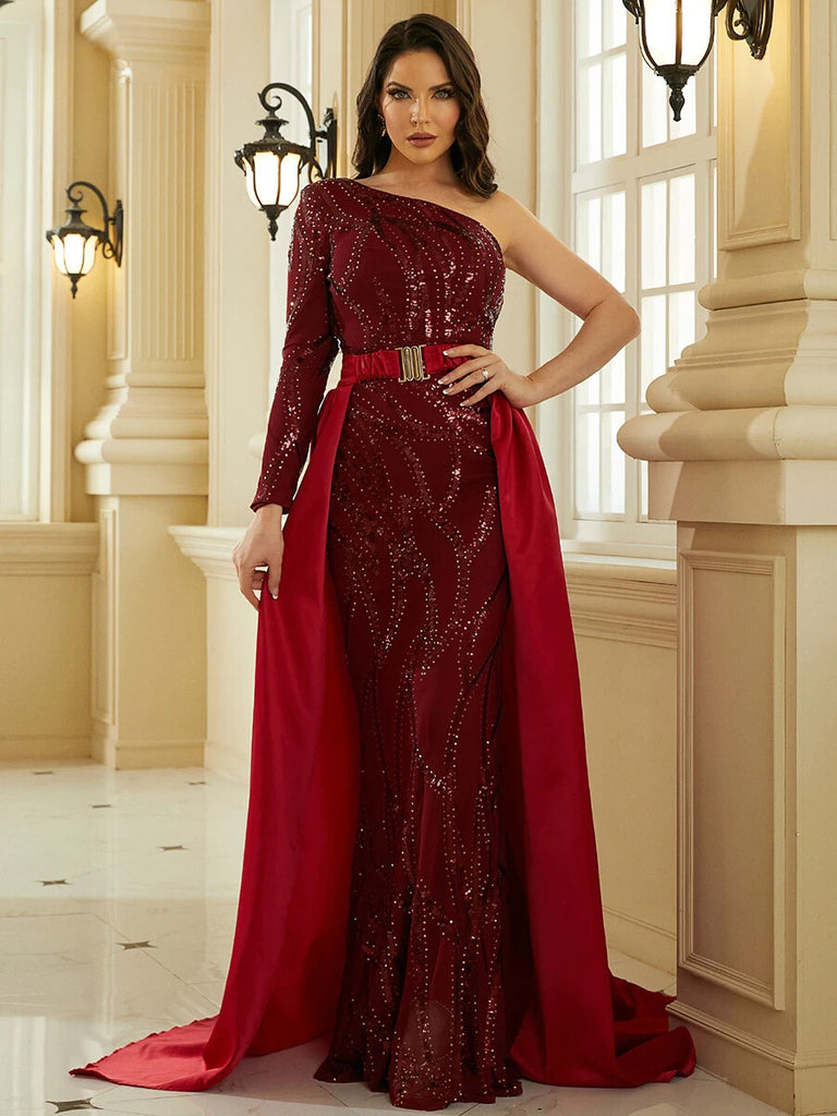 An Elegant burgundy  one-shoulder gown featuring intricate sequin detailing, a gold belt accent, and a dramatic cape for a regal and sophisticated look.