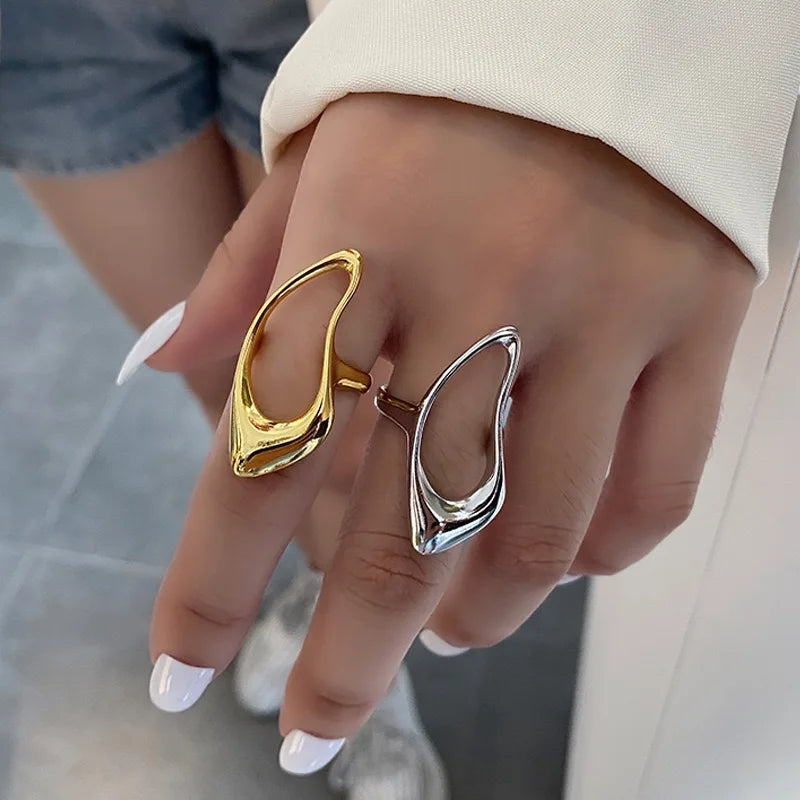 A pair of sculptural, open-design rings in polished gold and silver tones, showcasing a bold and modern aesthetic contemporary look.