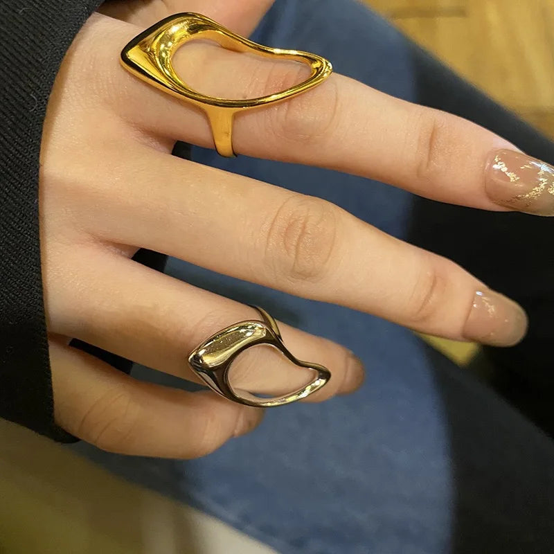 A pair of sculptural, open-design rings in polished gold and silver tones, showcasing a bold and modern aesthetic contemporary look.